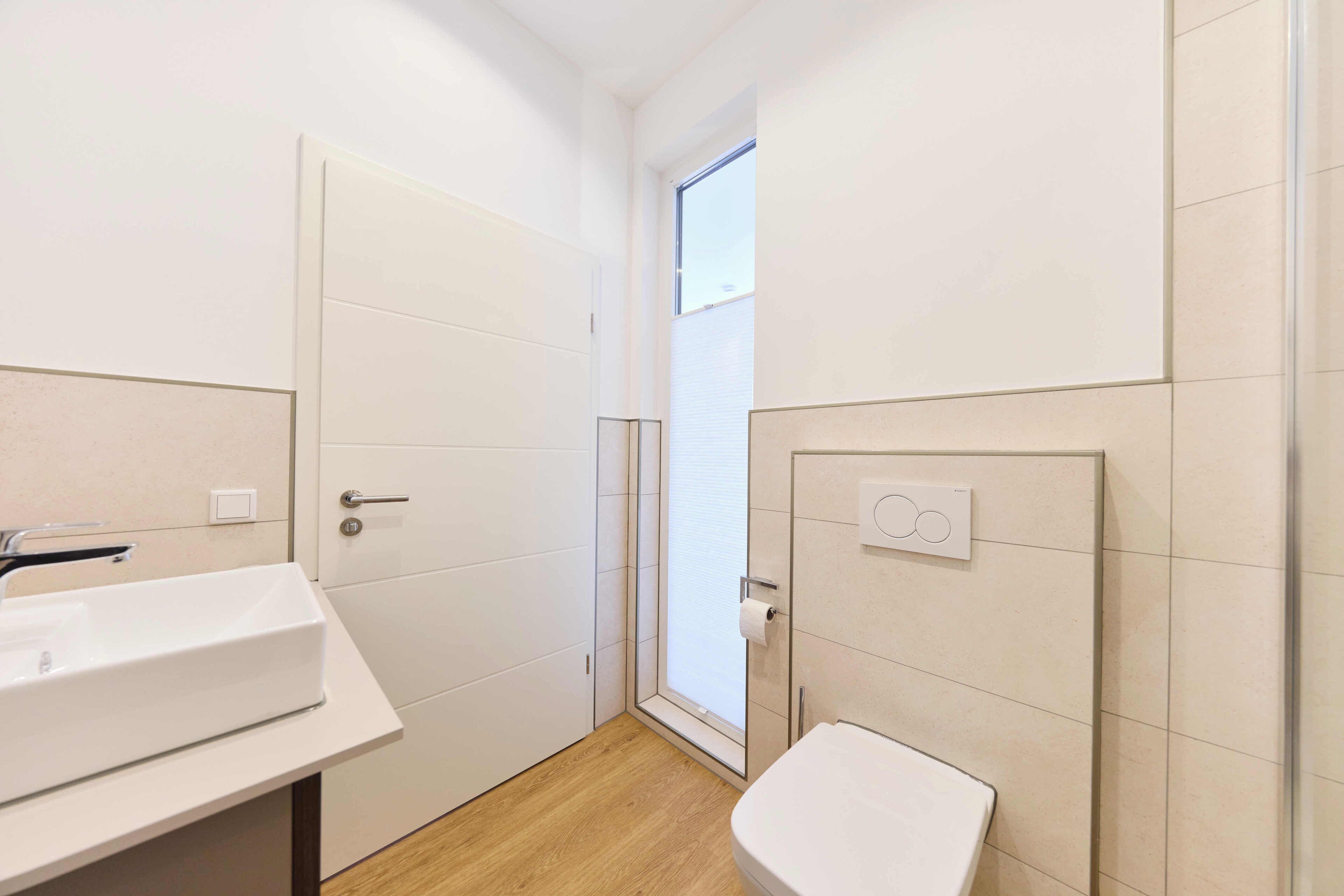 Ein kleines Badezimmer mit einem weißen Waschbecken, einer Toilette und einer Duschkabine aus Glas.