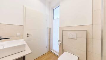 Ein kleines Badezimmer mit einem weißen Waschbecken, einer Toilette und einer Duschkabine aus Glas.