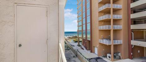 Un edificio de varios pisos con balcones, vista a la playa y zona de estacionamiento.