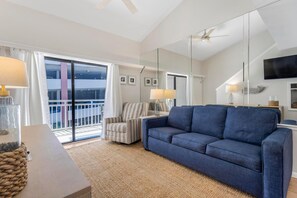 Ein modernes Wohnzimmer mit einem blauen Sofa, einem gestreiften Sessel, einem Glastisch und einem großen Spiegel.