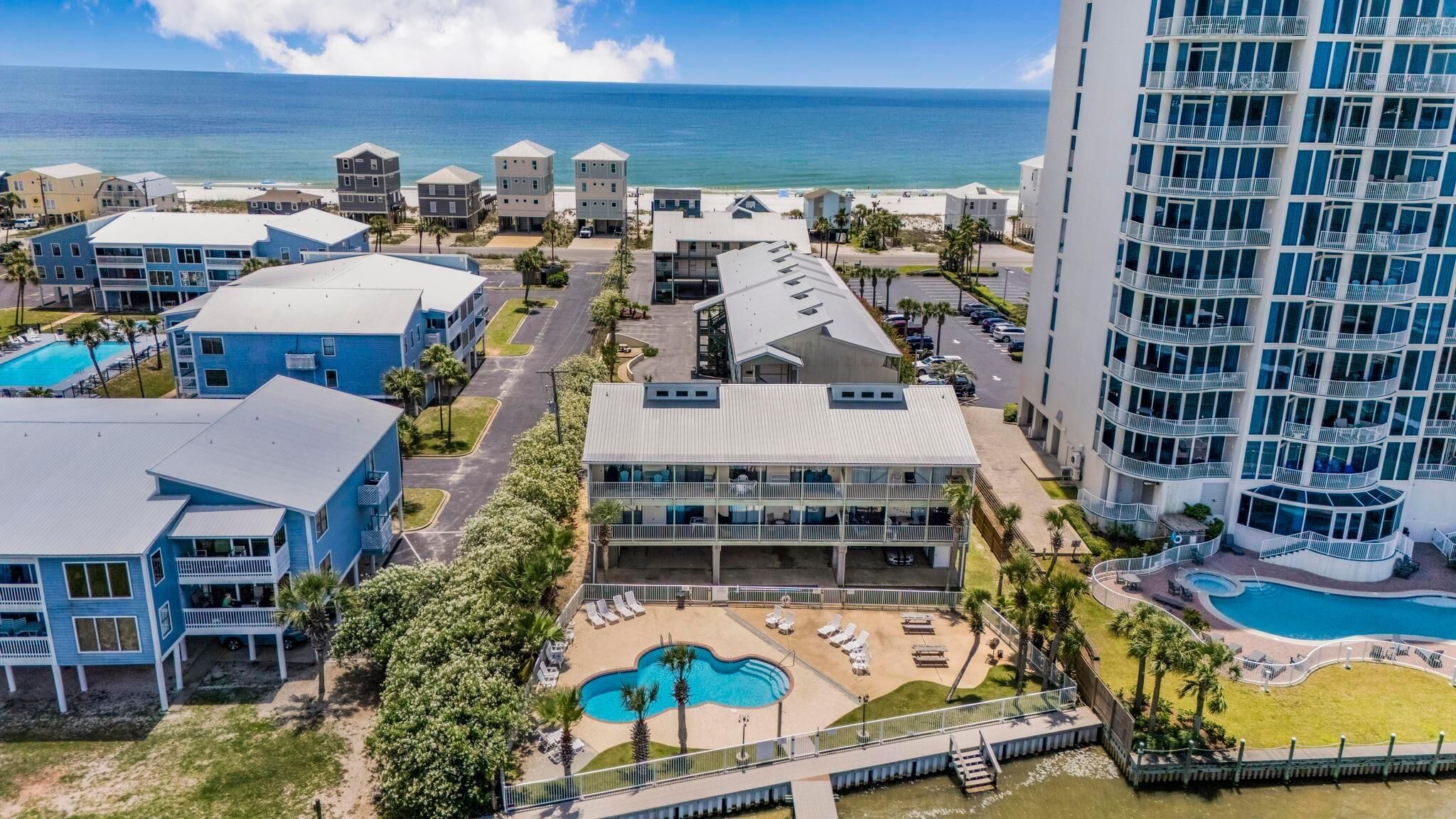 Um hotel à beira-mar com piscina, vários edifícios e vista para o oceano.