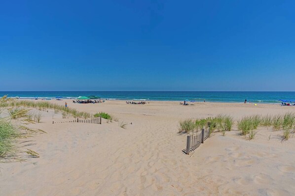 Ein Strand mit einer Holzstege, der zum Wasser führt, bewölkter Himmel und ruhiges Meer.