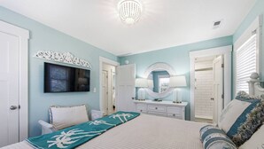 Ein Schlafzimmer mit Bett, Kommode, Spiegel und Fernseher.