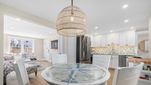 Een moderne keuken met witte kasten, een roestvrijstalen koelkast en een ronde eettafel met stoelen.
