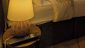 A hotel room with a bed, a lamp, a remote control, and a window with curtains. - Luxury 3BR Home 20 Mins to London Garden Wi-fi (Gravesend)