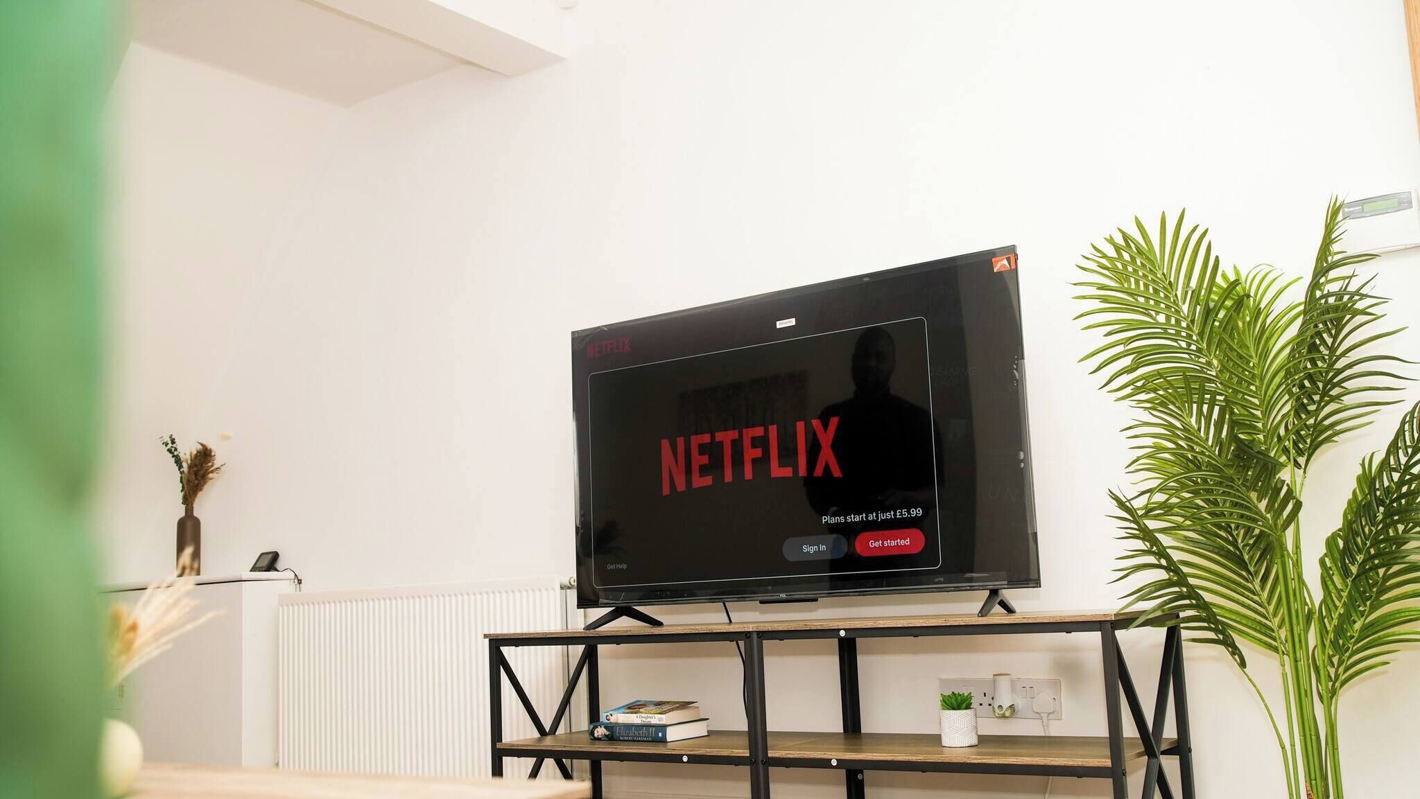 A flat-screen TV on a stand displaying the Netflix interface with a promotional offer.