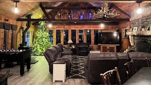 Ein gemütliches Blockhaus-Interieur mit Holzbalkendecke, Kamin, Fernseher und einem Kicker.