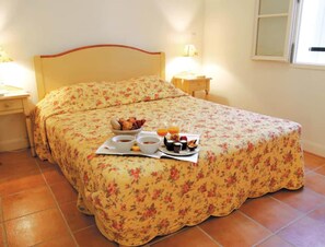 A bed with a floral bedspread, a bedside table with a lamp, and a tray with breakfast items. - Fayence Provencal House for 4 (Fayence)