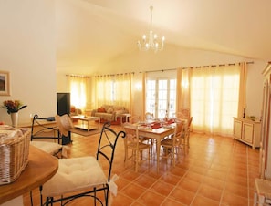 A spacious living area with a dining table set for four, surrounded by chairs. There is a television, a sofa, and a chandelier. - Fayence Provencal House for 4 (Fayence)
