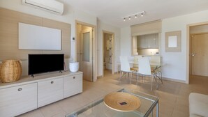 A modern living room with a flat-screen TV, a glass coffee table, and a wicker basket.