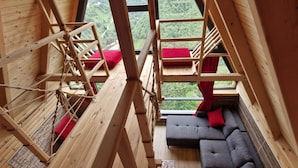 A wooden interior with a sofa and a view of greenery outside. - HAVALI BUNGALOWS (Camlihemsin)