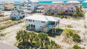 Une propriété située en bord de mer, comprenant plusieurs maisons, une terrasse couverte et une plage de sable.