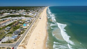 An aerial view of a coastal town with a long beach, houses, and a road running parallel to the shore. - High Tide Hideaway | Lux Ocean View in Kitty Hawk (Kitty Hawk)