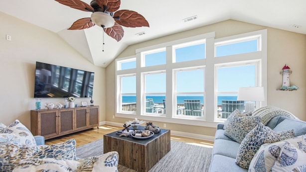 A living room with a large TV, wooden cabinet, and a coffee table. - High Tide Hideaway | Lux Ocean View in Kitty Hawk (Kitty Hawk)