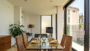 A dining area with a glass table, wicker chairs, a potted plant, and a view of the outside. - Suite Onda Reale - Acireale (Acireale)