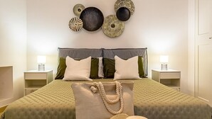 A bedroom with a bed, pillows, bedside tables, and wall decor. - Suite Onda Reale - Acireale (Acireale)