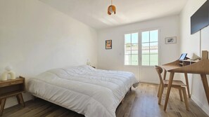 Ein Schlafzimmer mit Bett, Schreibtisch, Stuhl, Fenster und einem Bild an der Wand.