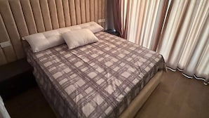 A modern bedroom with a large bed, a headboard, and a window with curtains. - lagoons and golf Arya view (Marsa Matrouh Governorate)