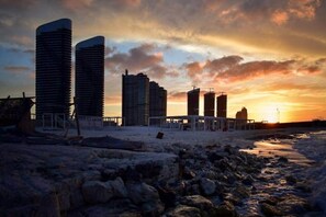 A coastal cityscape with high-rise buildings, a beach, and a sunset. - lagoons and golf Arya view (Marsa Matrouh Governorate)