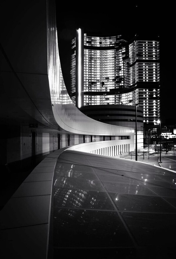 A modern building with a curved facade and illuminated windows at night.