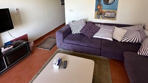 A living room with a sofa, a coffee table, a TV, and a painting on the wall. - lagoons and golf Arya view (Marsa Matrouh Governorate)
