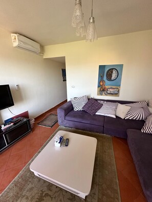 Una sala de estar con un sofá, una mesa de centro, un televisor y un cuadro en la pared.
