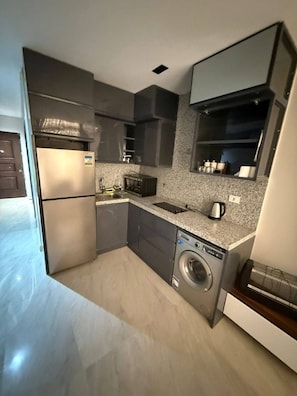 Une cuisine compacte équipée d’un lave-linge, d’un four à micro-ondes et d’un réfrigérateur.