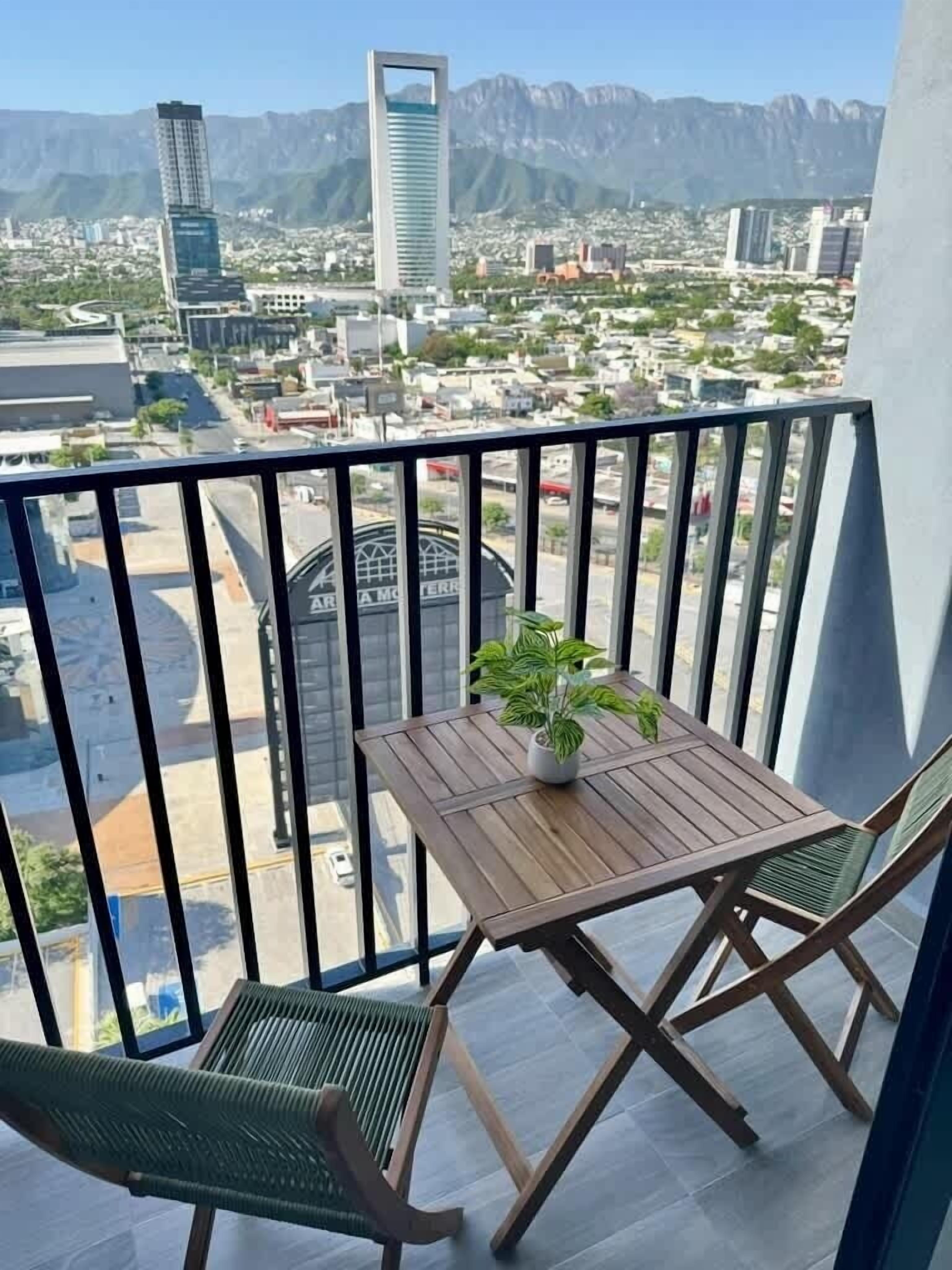 A balcony with a wooden table, two chairs, and a potted plant.