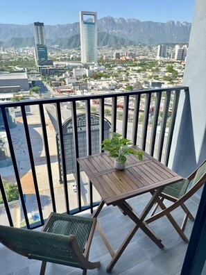 A balcony with a wooden table, two chairs, and a potted plant.