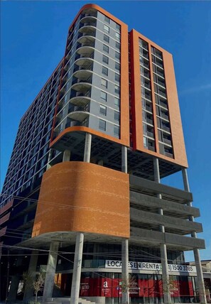 A multi-story building with balconies, a prominent orange facade, and a sign for 'LOCA ESEN RENTAL'.