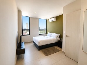 Ein modernes Schlafzimmer mit einem Bett, einem Fernseher, einem Fenster und einer Klimaanlage.