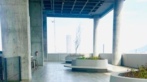 An indoor space with concrete pillars, a tiled floor, and planters with greenery. - Fundidora Loft w/Parking & AC, Near Arena (Monterrey)