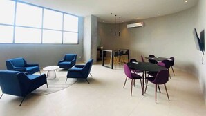 A modern room with a large window, a flat-screen TV, and a dining area with chairs and a table. - Fundidora Loft w/Parking & AC, Near Arena (Monterrey)