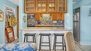 Una cocina con armarios de madera, encimera de granito y una isla integrada con taburetes de bar.