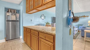 Cocina con armarios de madera, refrigerador de acero inoxidable y pared azul.