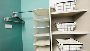 A closet with white shelves and hanging space, including a metal rack and baskets. - Comodo Loft/Ac/Tv/Wifi/2px (Monterrey)