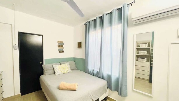 A bedroom with a bed, a ceiling fan, a window with curtains, a wardrobe, and a mirror. - Comodo Loft/Ac/Tv/Wifi/2px (Monterrey)