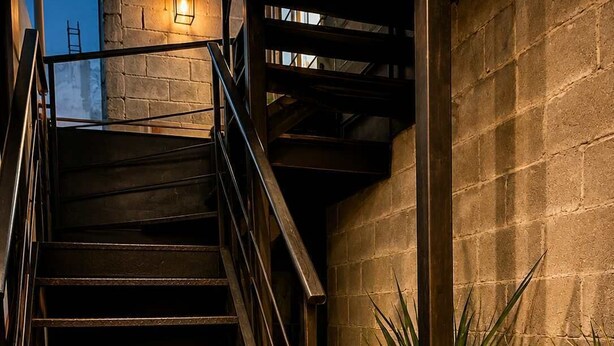 Eine Treppe mit Metallgeländern, einer Fußmatte mit dem Aufdruck 'HOME' und Topfpflanzen.
