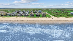 En fastighet vid kusten med hus som ligger direkt vid stranden, en sandstrand och utsikt över havet.