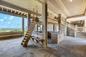 Un interior espacioso con una amplia escalera, vigas de madera y vistas a la playa.