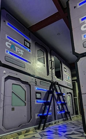 A futuristic interior with metallic walls, numbered doors, and a ladder. - Hotel Victoria Caps (Cartagena)