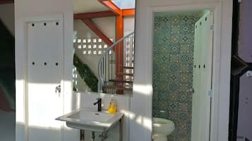 Casa de banho compacta com lavatório branco, sanita e espelho.
