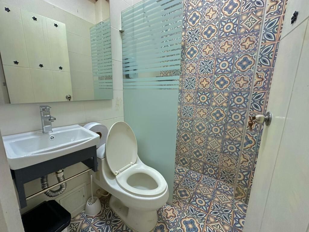 A bathroom with a toilet, sink, and mirror.