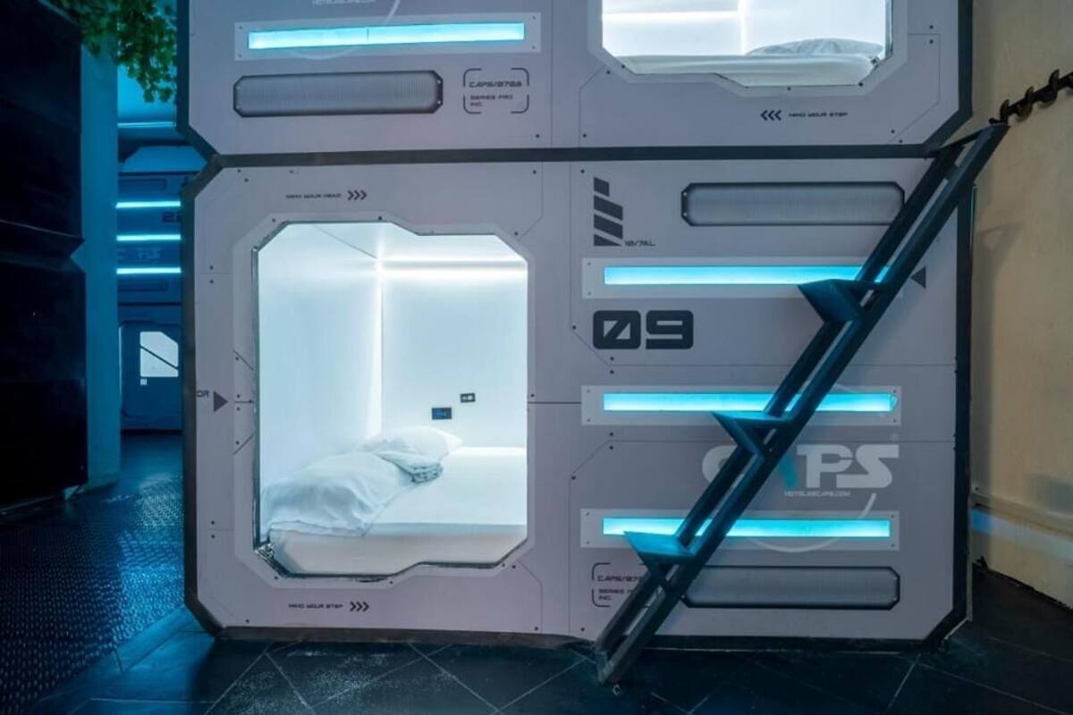 A futuristic room with a bed, a chair, and a staircase.