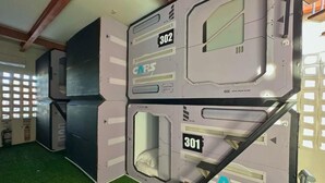 Etagenbetten mit den Nummern 302 und 301, einem Metallgeländer und einem grünen Kunstpflasterboden.