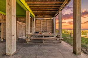 An outdoor wooden structure with a picnic table, benches, and a view of the beach at sunset. - Beachfront 5BR | Gulf Views + Game Room with Pool Table (Port Bolivar)