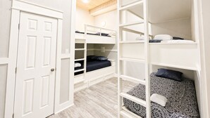 A room with bunk beds, a white door, and a wooden ceiling. - Beachfront 5BR | Gulf Views + Game Room with Pool Table (Port Bolivar)