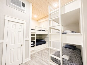 A room with bunk beds, a white door, and a wooden ceiling. - Beachfront 5BR | Gulf Views + Game Room with Pool Table (Port Bolivar)