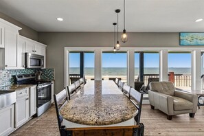 A kitchen with a large island, white cabinets, and a view of the beach. - Beachfront 5BR | Gulf Views + Game Room with Pool Table (Port Bolivar)