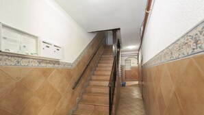 Una scala con corrimano, pareti piastrellate e una bacheca con avvisi.